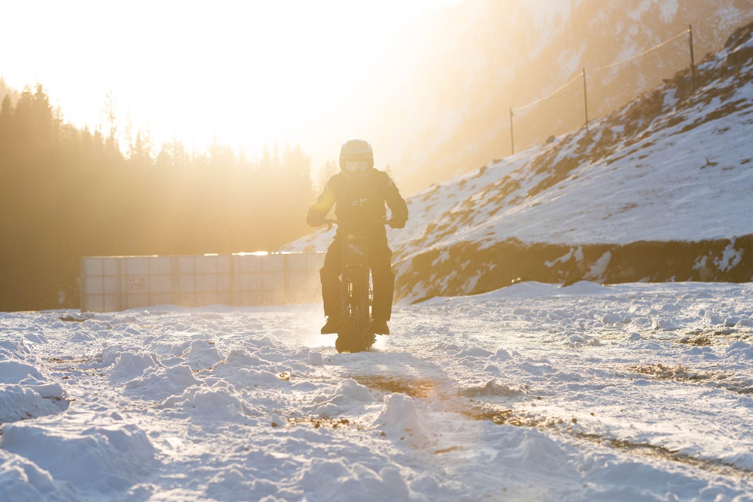 Rider heading into low winter sun on a Riding’times electric motorbike with the snow track kit