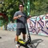 Rider standing over a Punk Rebel electric scooter beside a graffiti wall