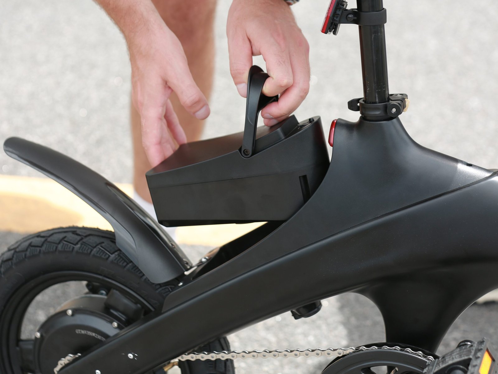 Hands lifting the removable battery pack out of the frame of a black Hiboy C1 folding electric bike