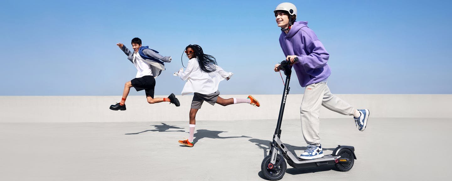 Three friends with the Segway E3 Pro electric scooter on a sunny street