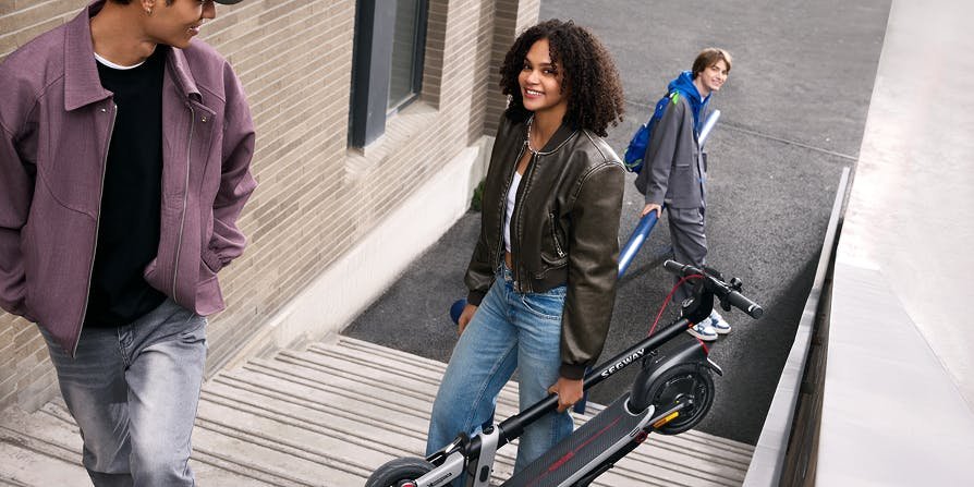 Commuters carrying the folded Segway E3 Pro electric scooter down steps