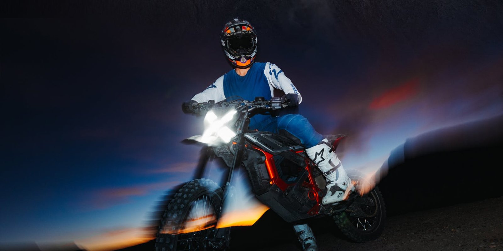 Rider on the Segway Xaber 300 electric dirt bike at dusk with the headlight on