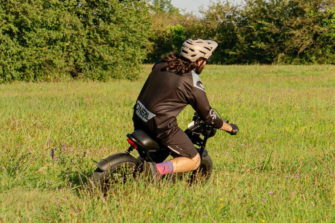 Rider crouched beside the Riding’times Z8 Pro electric bike in a meadow