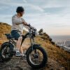 Rider standing with the Riding’times Z8 Pro electric bike on a hilltop above a city