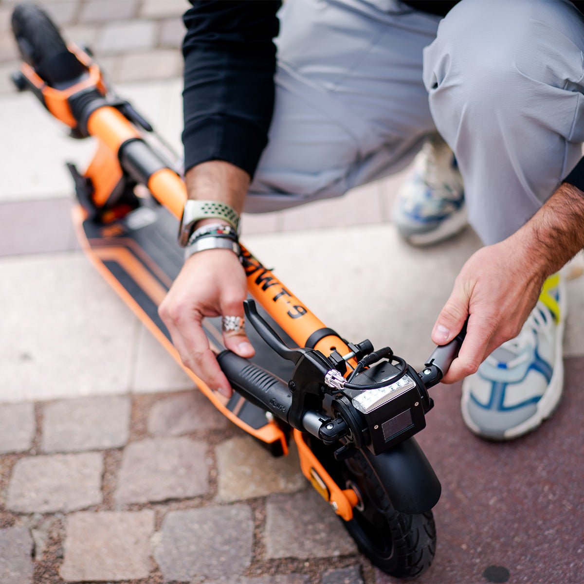Rider carrying the folded E-TWOW GT Sport electric scooter through the city