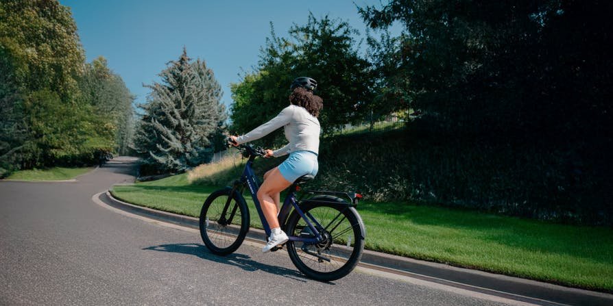 Rider climbing a tree-lined road on the Segway Myon electric bike
