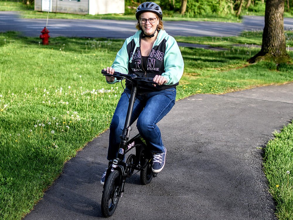 Rider in a helmet smiling on a black Hiboy C1 folding electric bike on a park path