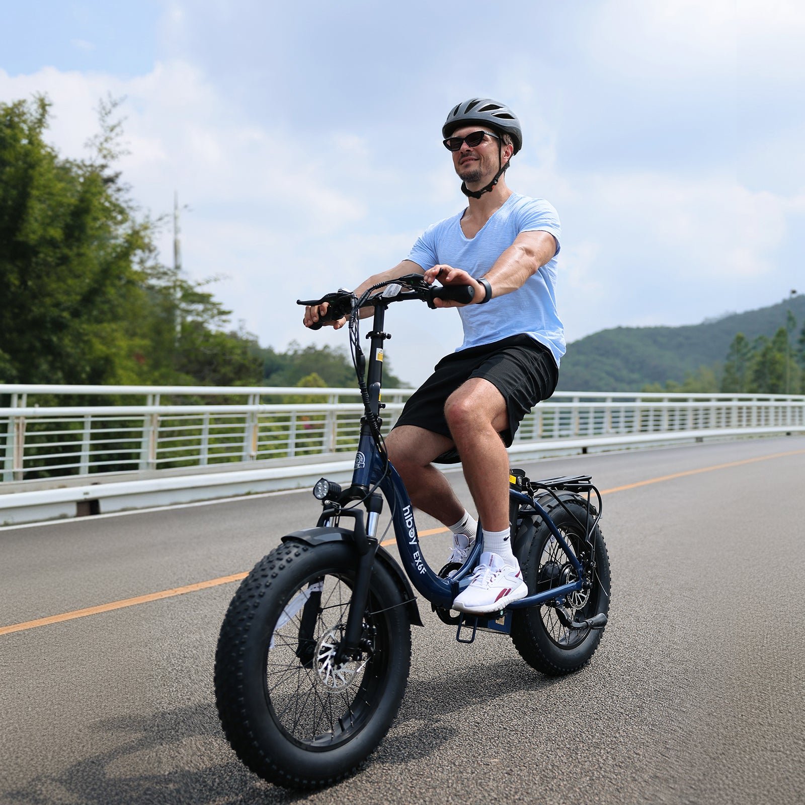 Rider in a helmet on a navy Hiboy EX6F folding electric bike crossing a bridge