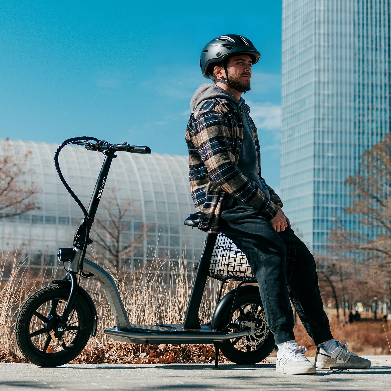 Rider resting on the seat of the Hiboy ECOM 14 electric scooter with a basket behind