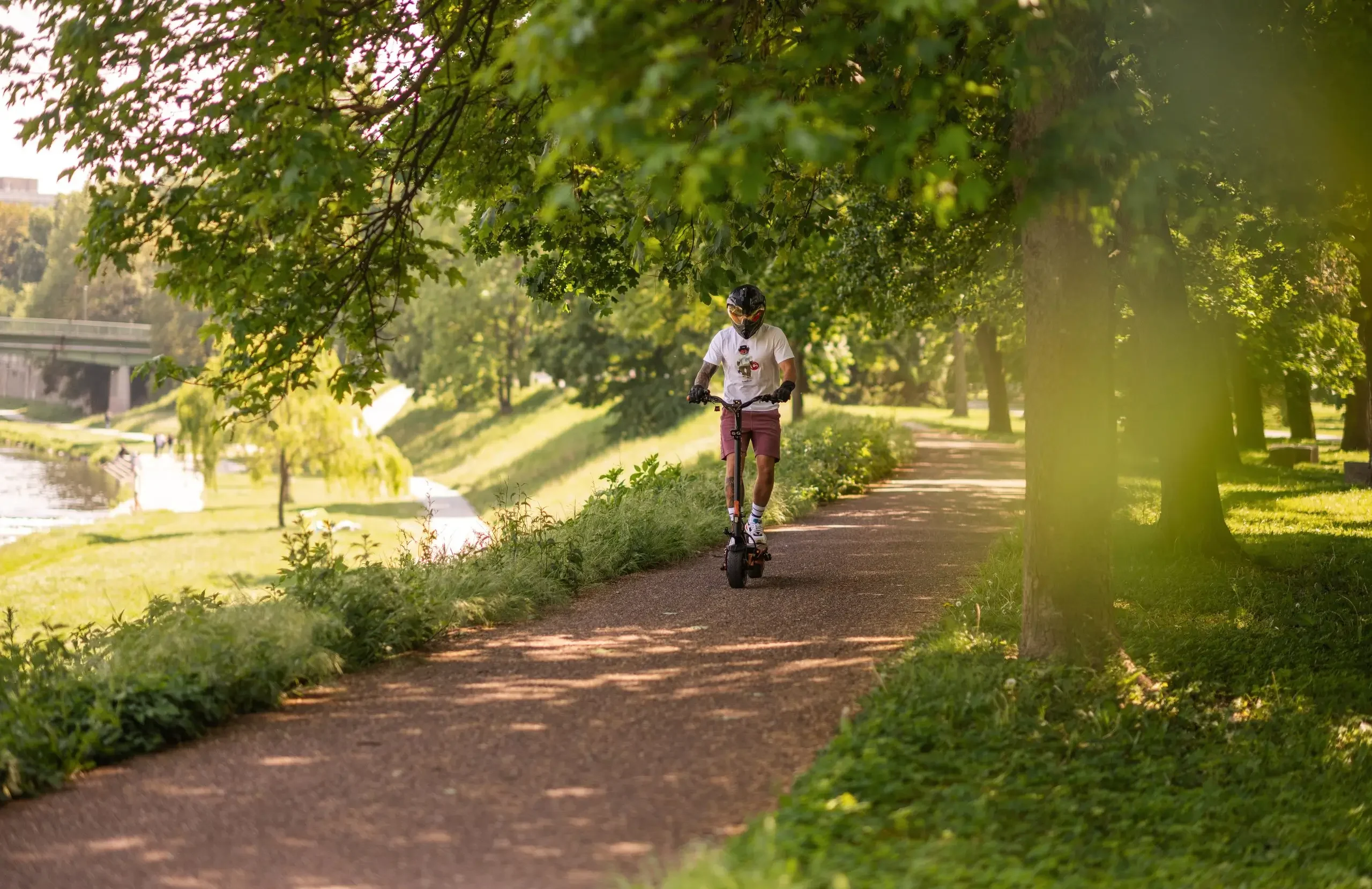 Rider on the Teverun Blade GT II+ electric scooter along a riverside path