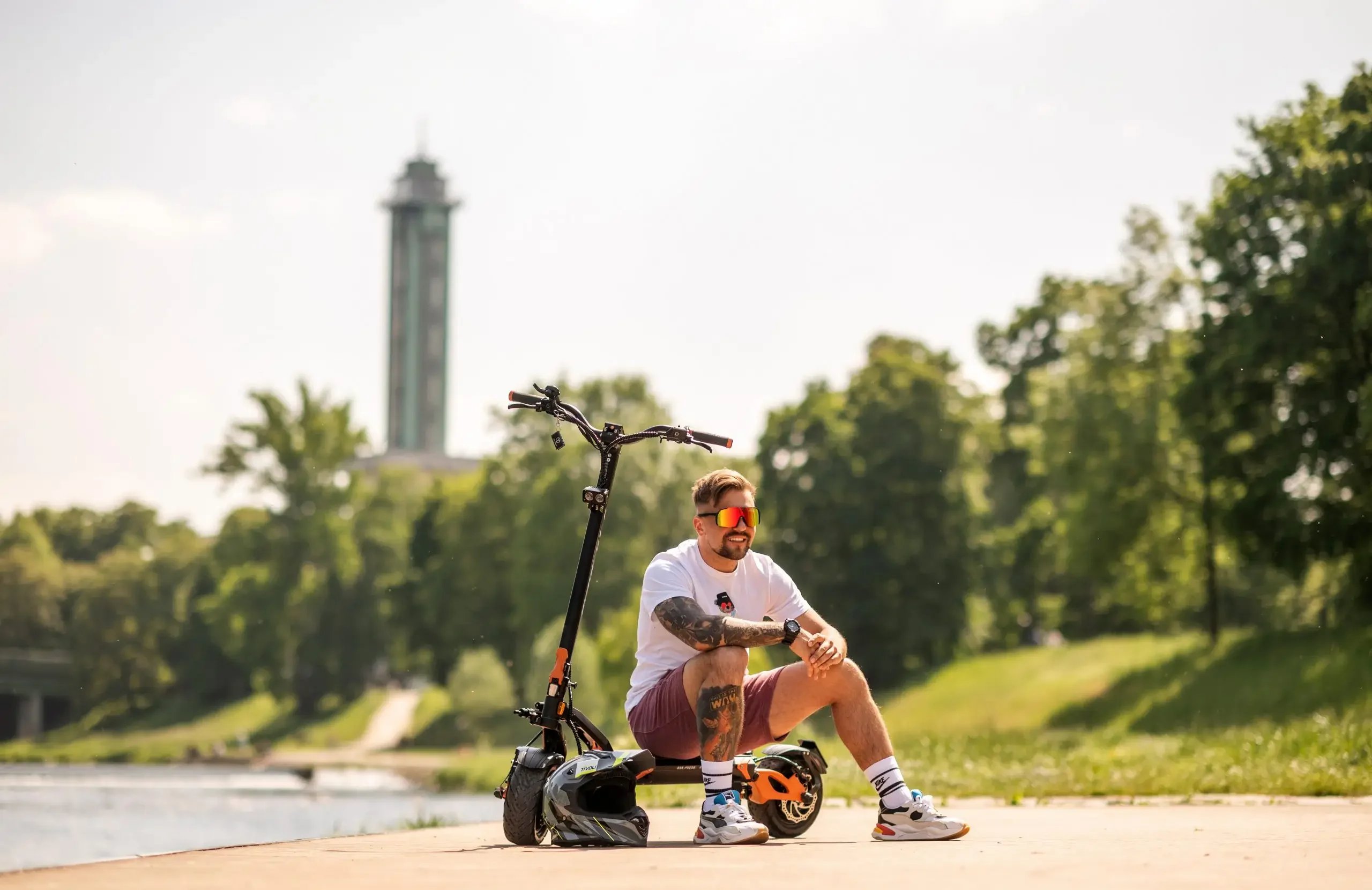 Rider sitting beside the Teverun Blade GT II+ electric scooter on the waterfront