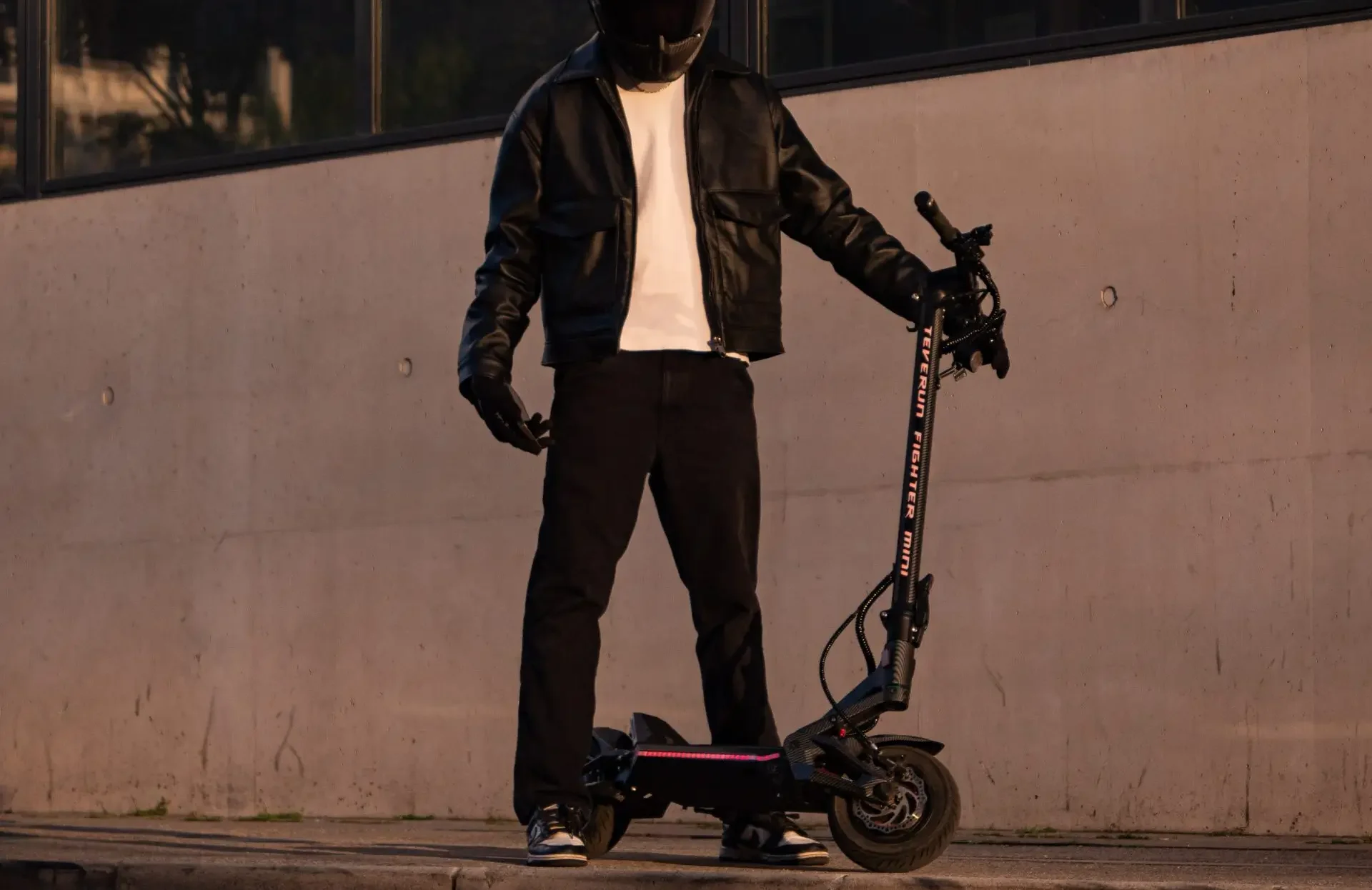 Rider standing with the Teverun Fighter Mini Pro electric scooter at dusk